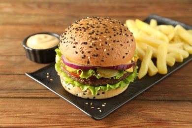 Photo of Burger with delicious patty, french fries and sauce on wooden table, closeup