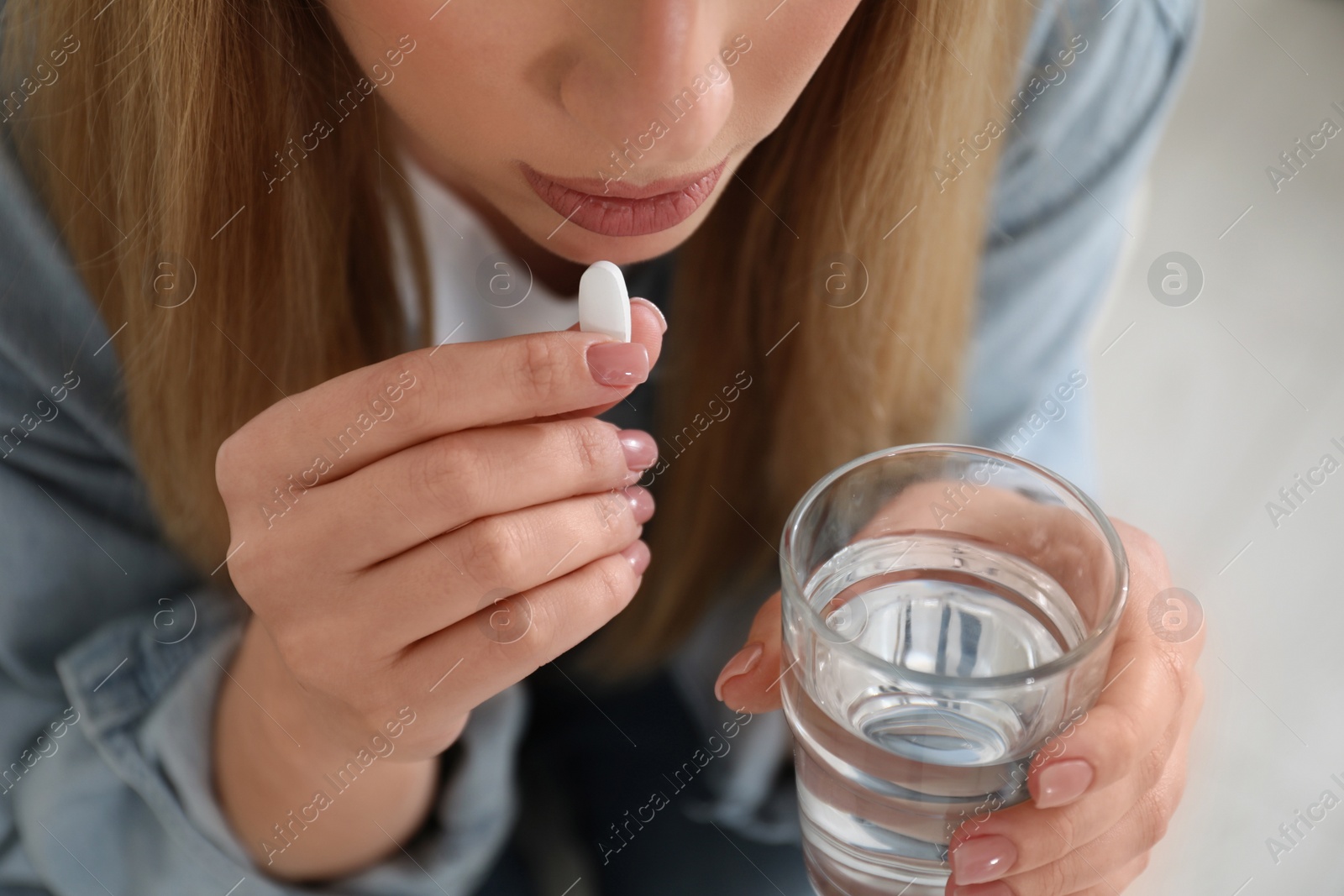 Photo of Young woman taking abortion pill on blurred background, closeup