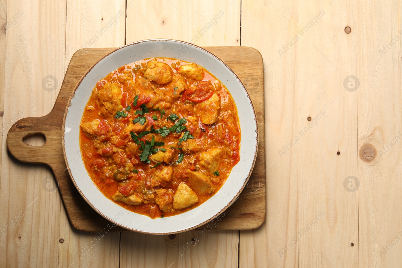 Photo of Delicious chicken curry on wooden table, top view. Space for text