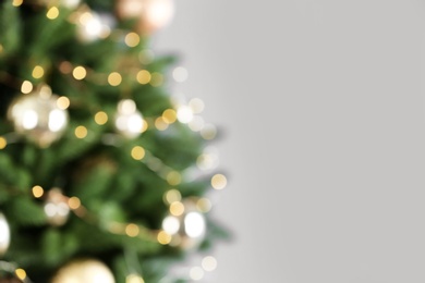 Photo of Beautiful Christmas tree with lights against grey background, blurred view. Space for text