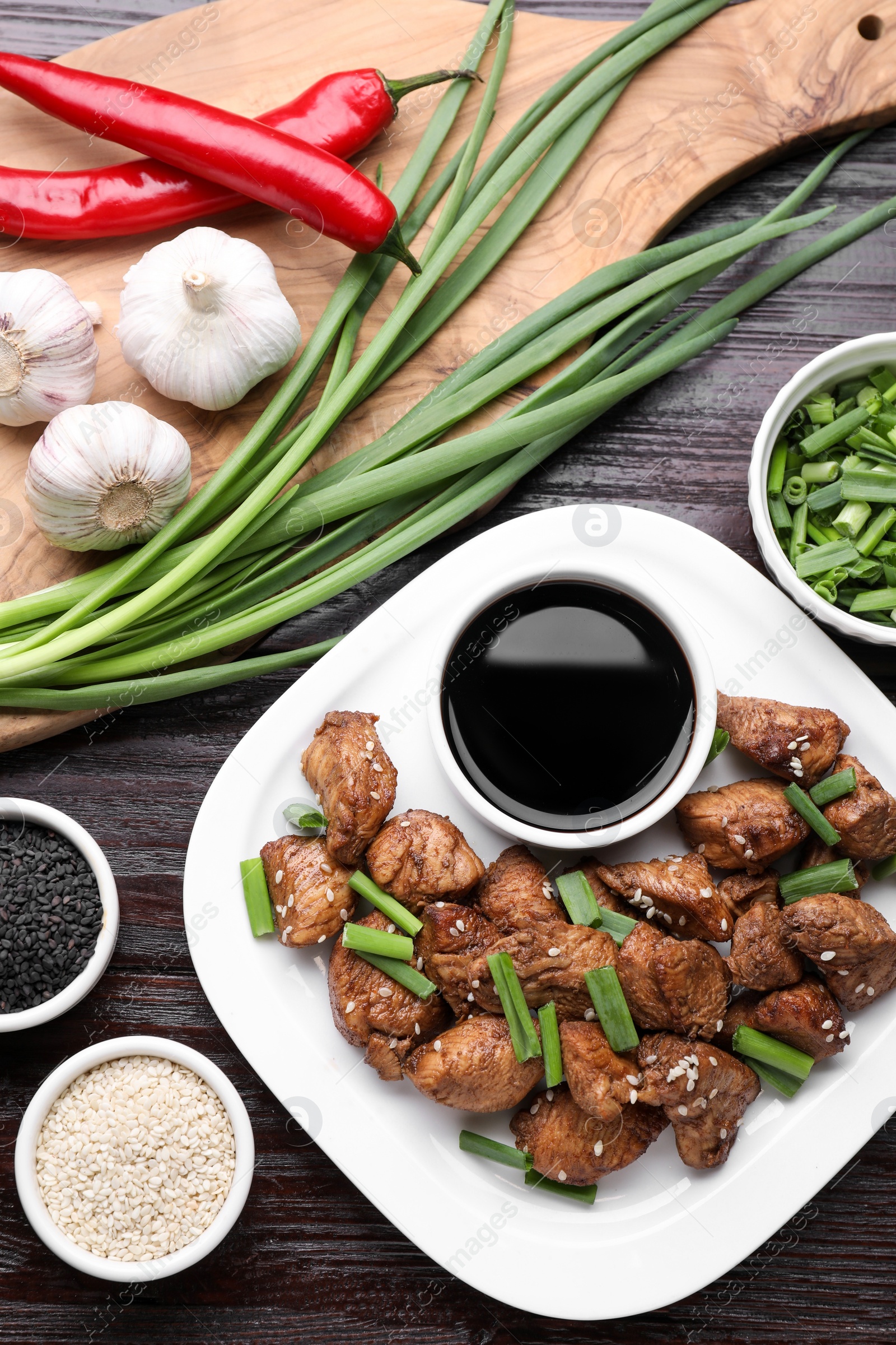 Photo of Tasty soy sauce, roasted meat and ingredients on wooden table, flat lay