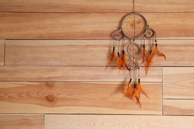 Photo of Beautiful dream catcher hanging on wooden wall, space for text