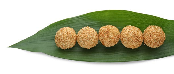 Photo of Delicious sesame balls and green banana leaf on white background
