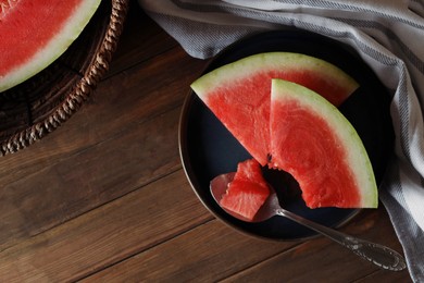 Photo of Sliced fresh juicy watermelon and spoon on wooden table, flat lay. Space for text