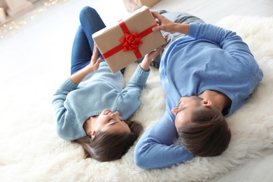 Photo of Young couple with Christmas gift at home