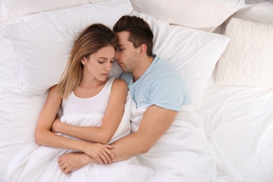 Photo of Young couple sleeping on soft pillows in bed at home