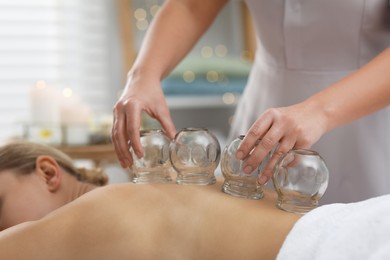 Photo of Therapist giving cupping treatment to patient indoors, closeup
