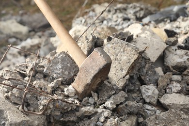 Photo of Sledgehammer on pile of broken stones outdoors, closeup