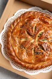 Photo of Tasty homemade pie in box on light table, top view