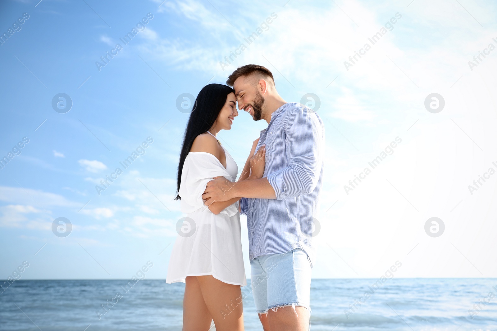 Photo of Happy young couple near sea on sunny day. Beach holiday