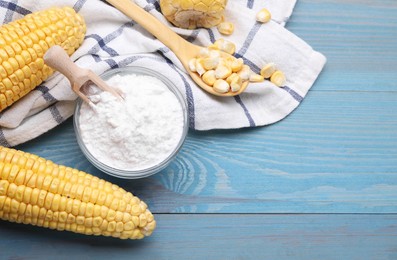Photo of Bowl with corn starch, ripe cobs and kernels on light blue wooden table, flat lay. Space for text