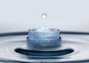 Jar of cosmetic product and splashing water on light background. Space for design