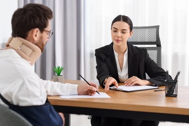 Injured man signing document in lawyer's office, selective focus