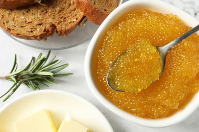 Fresh pike caviar in bowl, bread, rosemary and butter on white table, flat lay