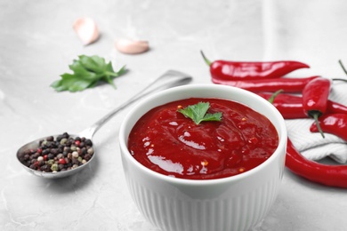 Photo of Bowl of hot chili sauce and ingredients on table