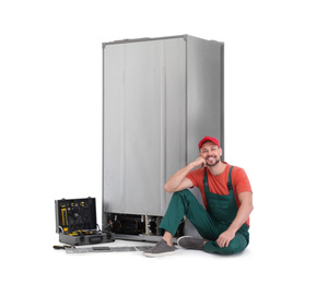 Photo of Male technician repairing refrigerator on white background