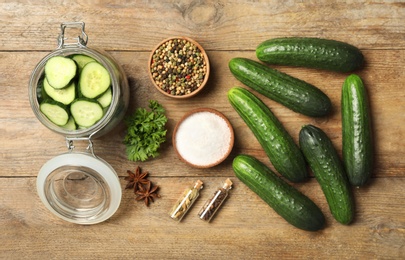 Photo of Pickling jar with fresh ripe cucumbers and spices on wooden table, flat lay