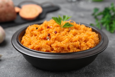 Photo of Bowl with mashed sweet potatoes on grey table