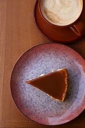 Photo of Cup of coffee and slice of cake on wooden table, top view