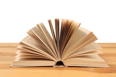 Photo of Open book on wooden table against white background. Library material