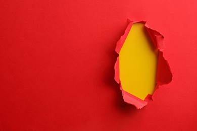 Photo of Hole in red paper on yellow background, space for text