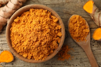 Photo of Aromatic turmeric powder and raw roots on wooden table, flat lay