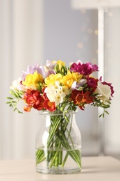 Photo of Beautiful bright spring freesia flowers in vase on table. Space for text