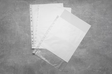 Photo of Punched pockets with paper sheets on grey table, flat lay. Space for text