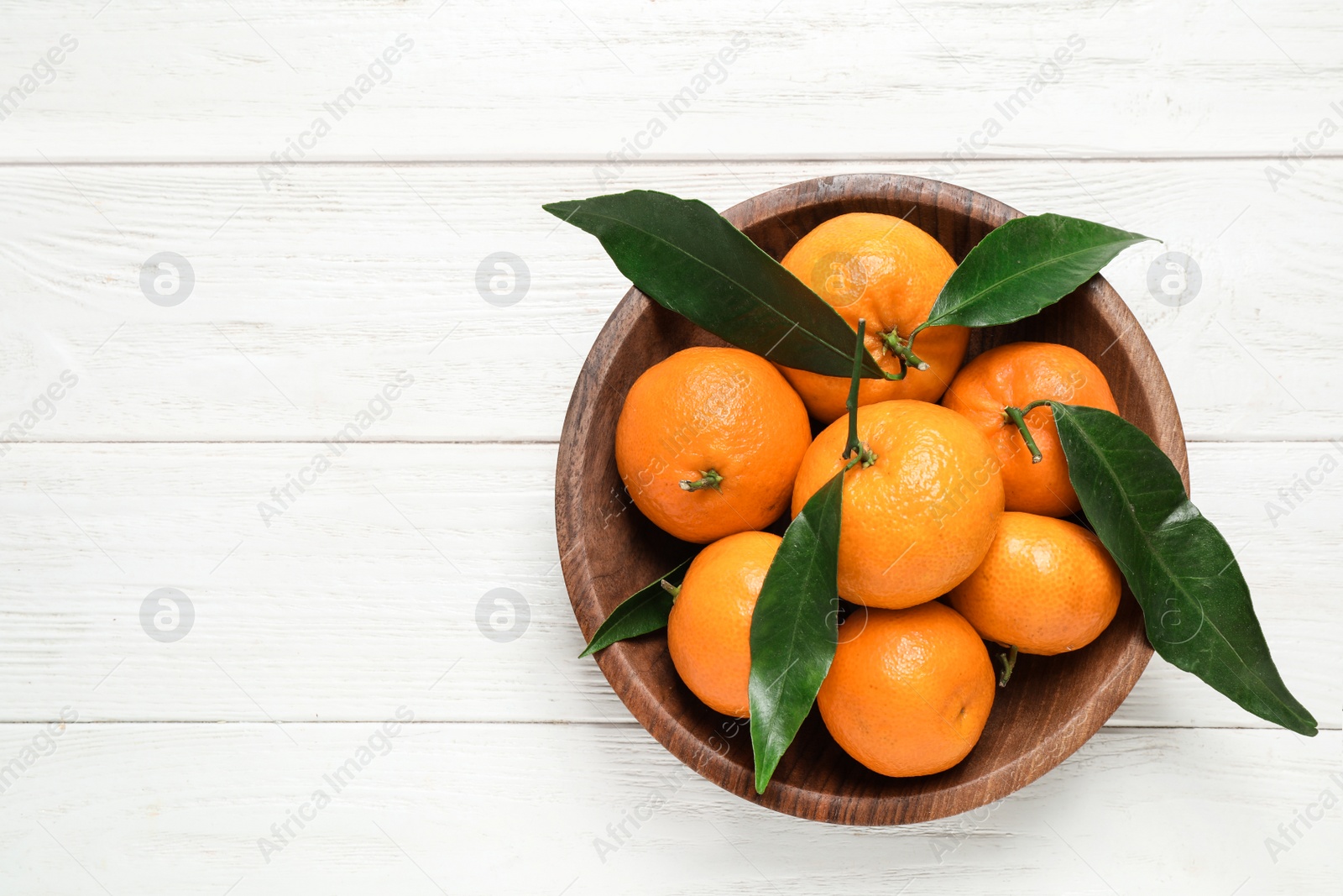 Photo of Fresh ripe tangerines with leaves and space for text on white wooden table, top view. Citrus fruit