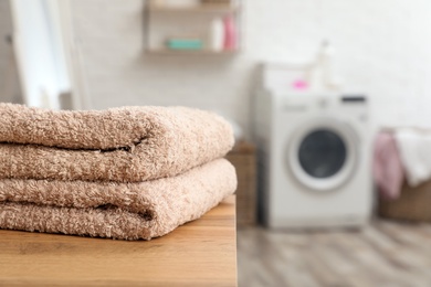 Photo of Stack of towels on table against blurred background, space for text