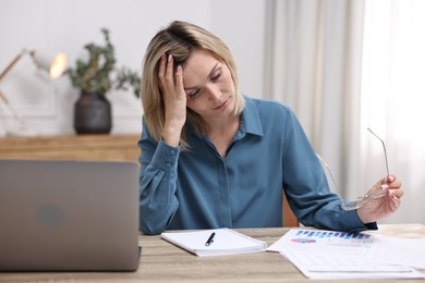 Photo of Overwhelmed woman with glasses sitting at table in office