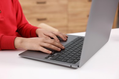 Photo of E-learning. Girl using laptop during online lesson at table indoors, closeup