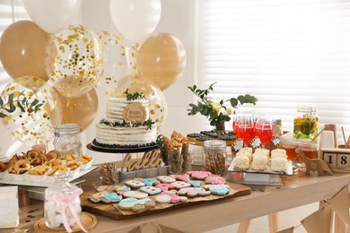 Photo of Baby shower party. Different delicious treats on wooden table and decor indoors
