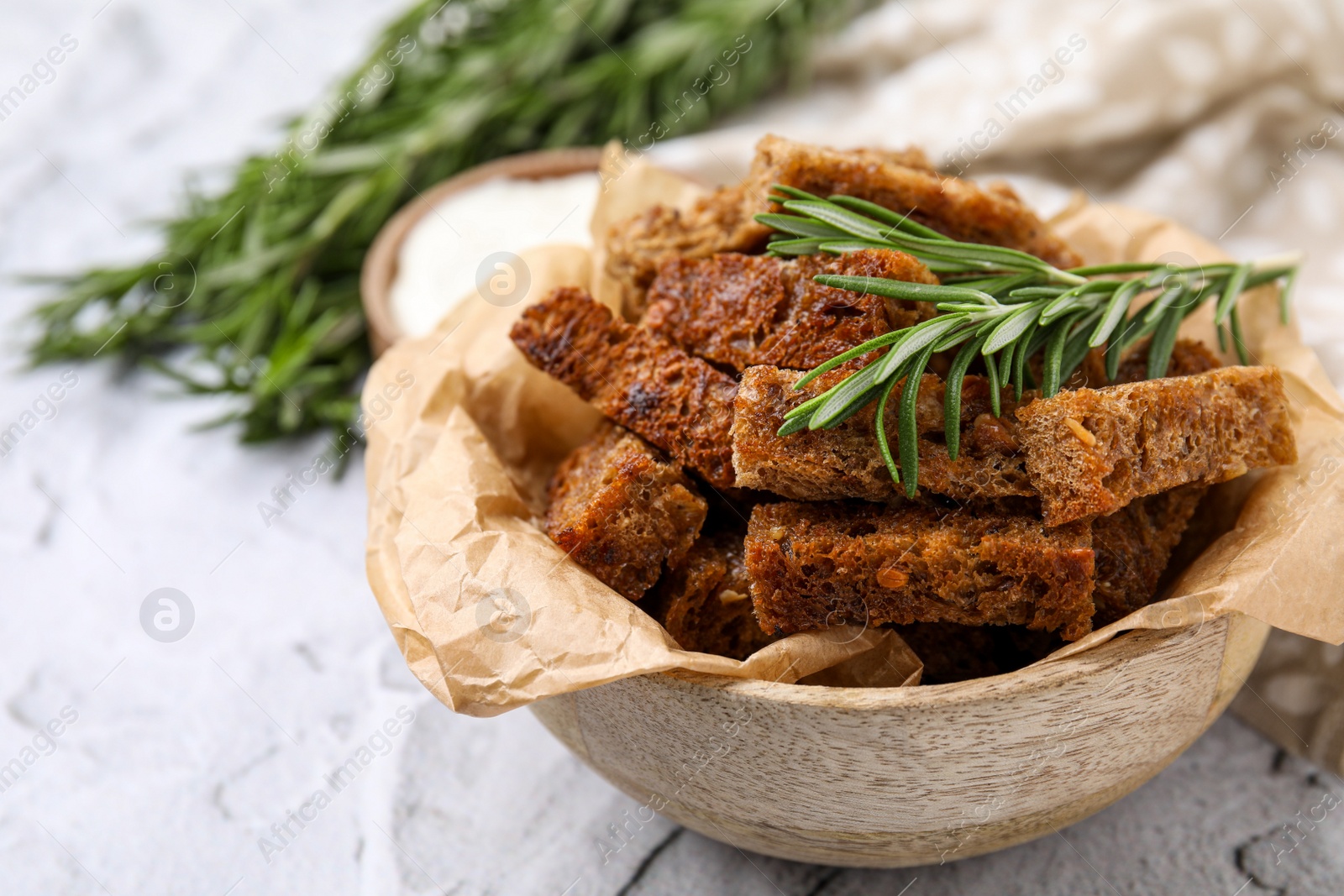 Photo of Crispy rusks with rosemary on white table. Space for text