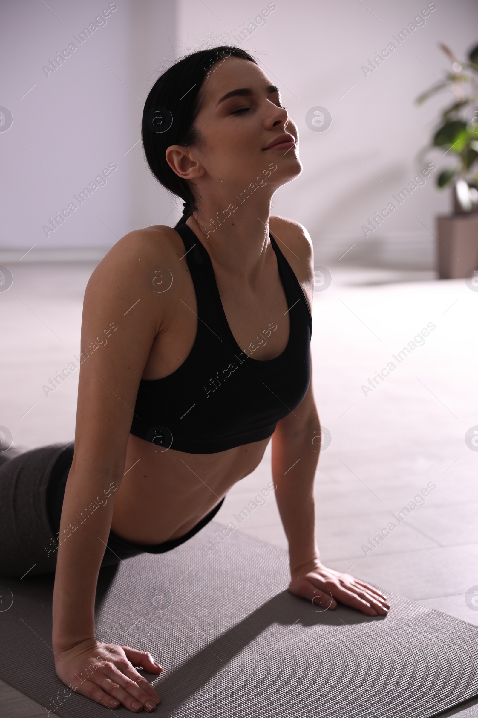 Photo of Young woman practicing cobra asana in yoga studio. Bhujangasana pose