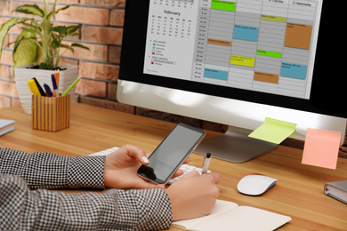 Photo of Woman using calendar app on computer in office, closeup