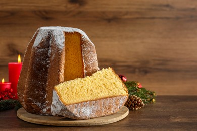 Photo of Delicious Pandoro cake with powdered sugar and Christmas decor on wooden table, space for text. Traditional Italian pastry
