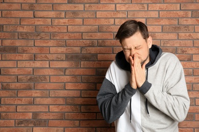 Photo of Man suffering from cold near brick wall. Space for text