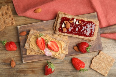 Photo of Fresh rye crispbreads with different toppings on wooden table, flat lay