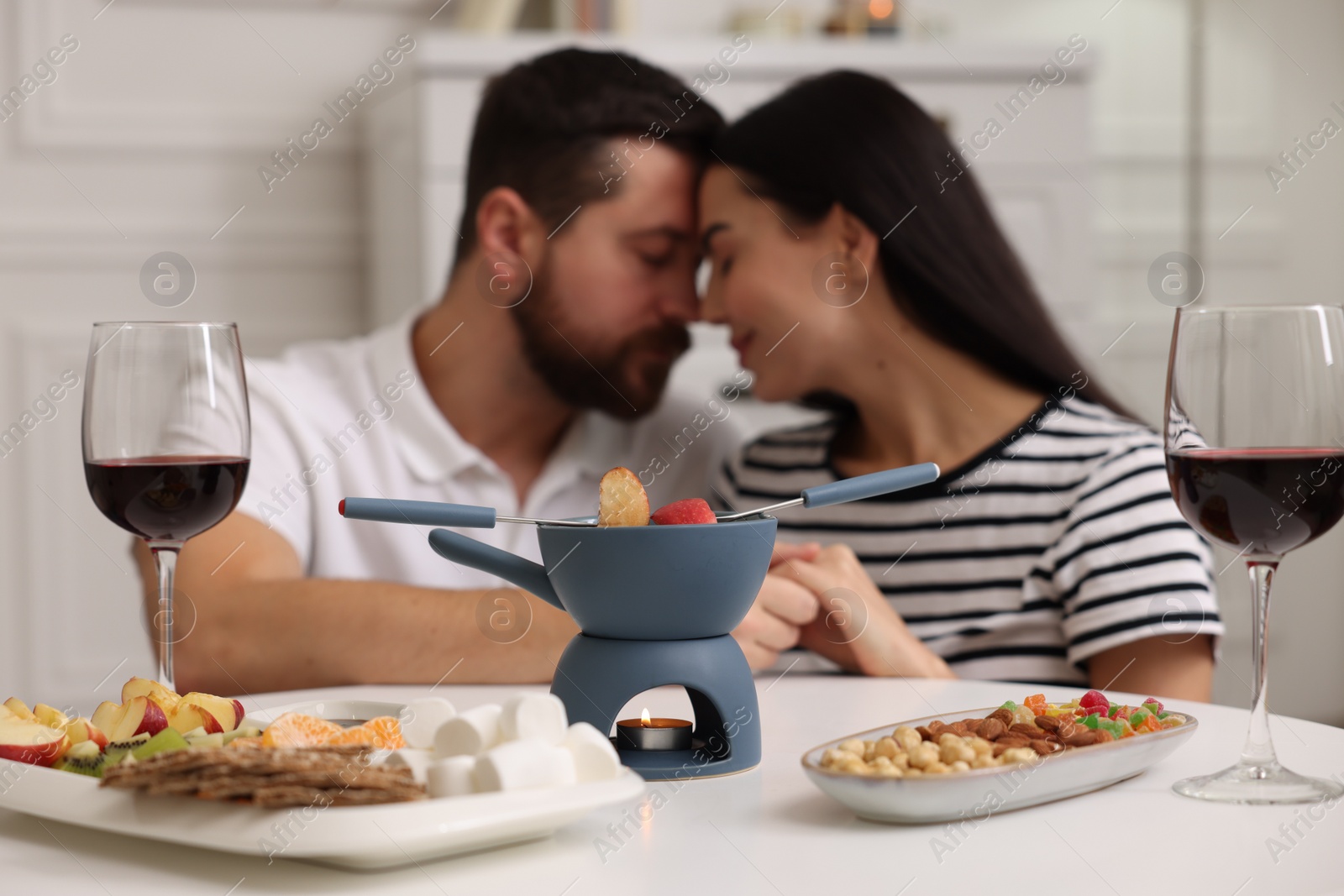 Photo of Romantic date with fondue. Couple enjoying each other at home, selective focus