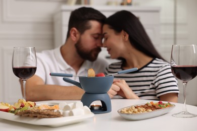 Photo of Romantic date with fondue. Couple enjoying each other at home, selective focus