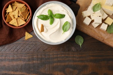 Photo of Delicious tofu sauce served with crunchy snack on wooden table, flat lay. Space for text