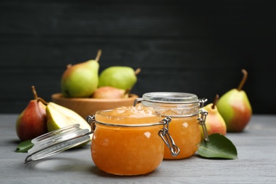Photo of Delicious pear jam and fresh fruits on grey wooden table