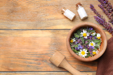 Photo of Flat lay composition with mortar and different healing  herbs on wooden table, space for text