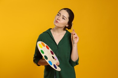 Photo of Woman with painting tools on yellow background. Young artist