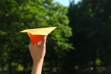 Photo of Woman holding paper plane outdoors, closeup. Space for text