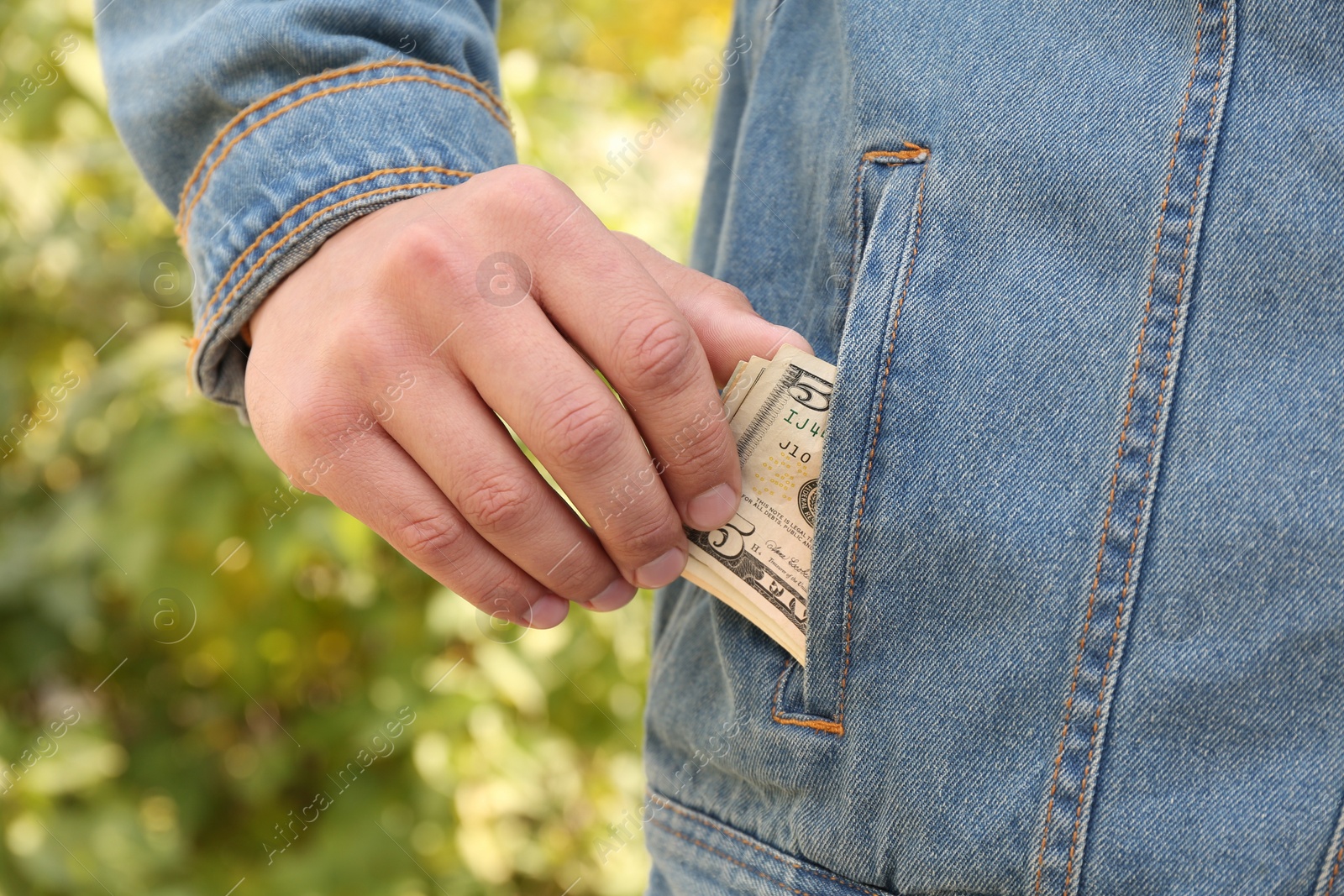 Photo of Man putting money into pocket of jacket outdoors, closeup