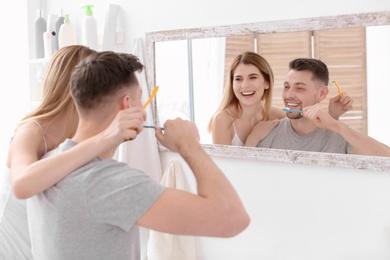 Photo of Young couple brushing teeth together in bathroom