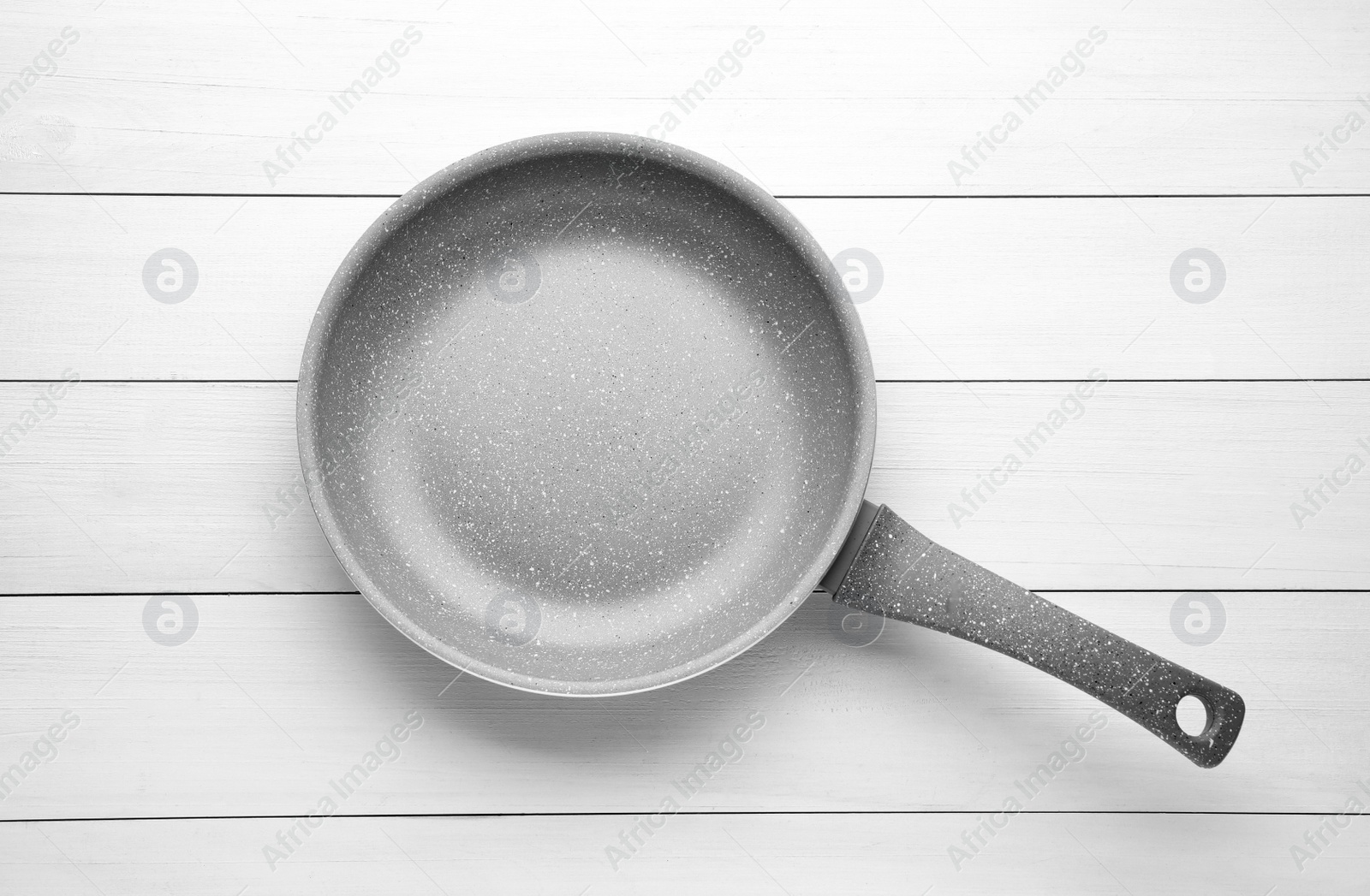 Photo of New non-stick frying pan on white wooden table, top view