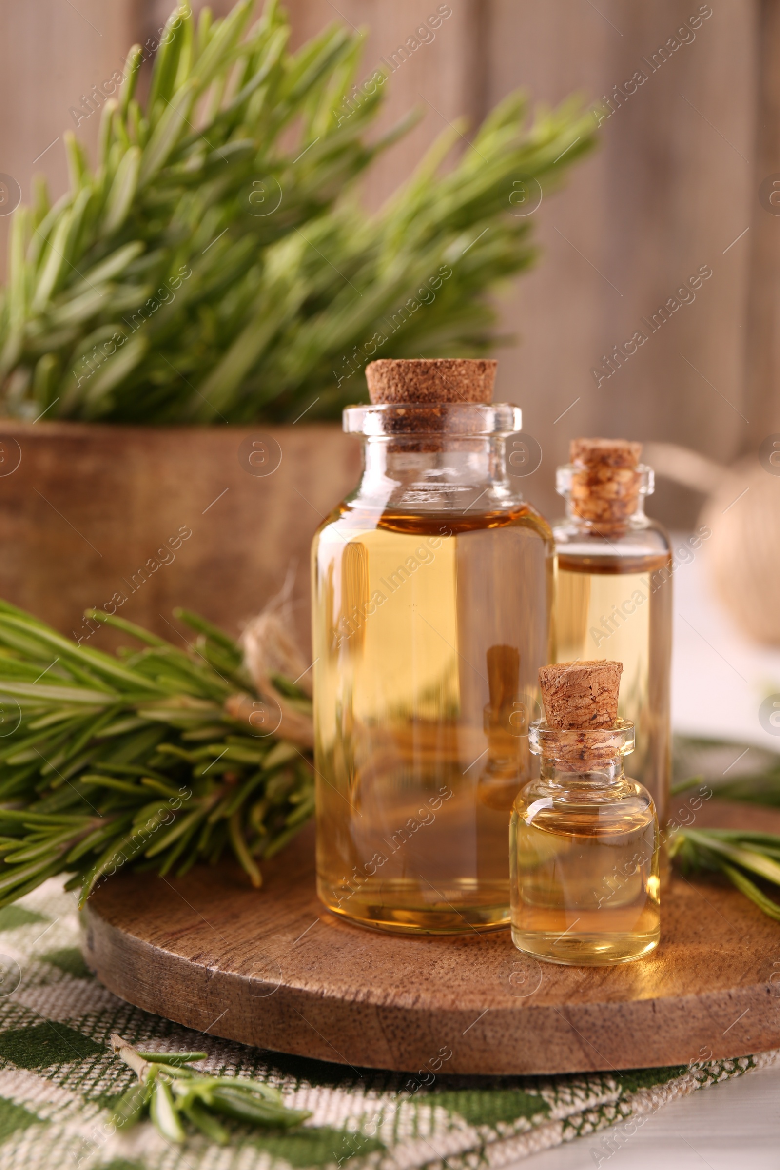 Photo of Essential oil in bottles and rosemary on table